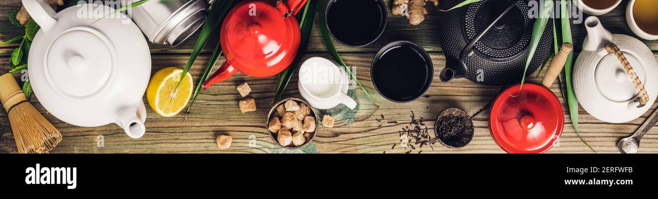 Vari tè e teiera composizione, erbe essiccate, tè verde, nero e tè matcha su sfondo tavola di legno, piatto posa, spazio copia Foto Stock