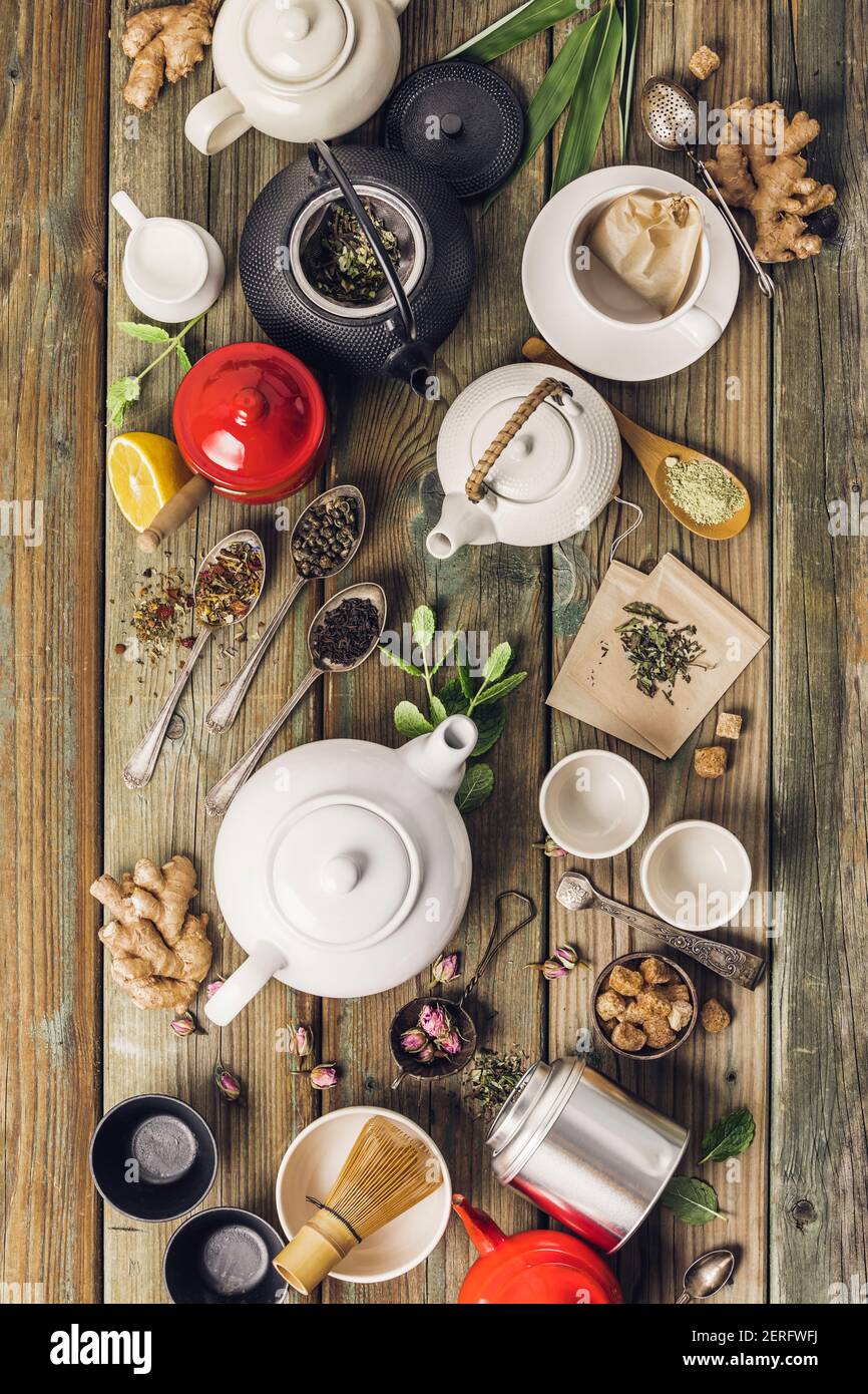 Vari tè e teiera composizione, erbe essiccate, tè verde, nero e tè matcha su fondo tavola di legno, piatto Foto Stock