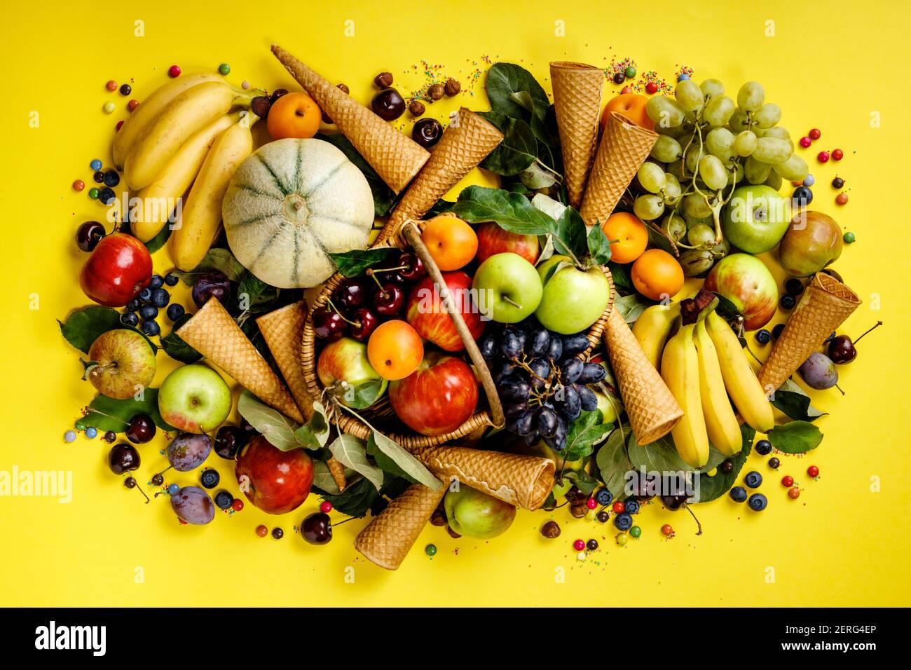 Piatto di frutta e bacche e coni gelato su sfondo giallo. Vista dall'alto. Foto Stock