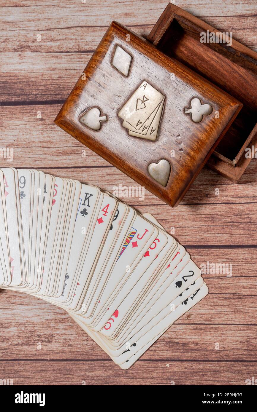 Scatola di legno per le carte e le carte del poker si è sformato fuori su un tavolo di legno. Foto Stock