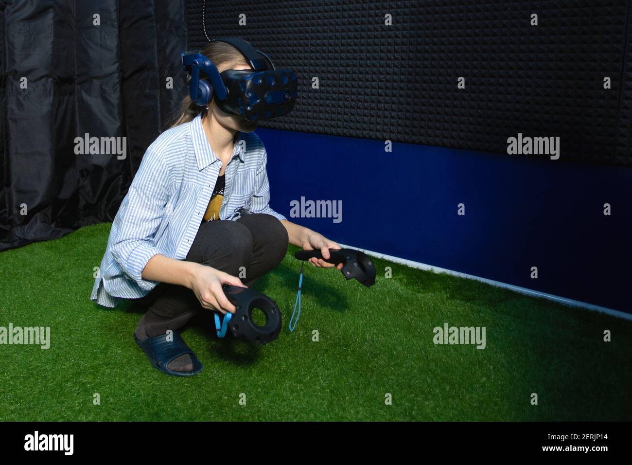 Giovane ragazza teenager che indossa occhiali di realtà virtuale seduto sul pavimento utilizzando controller che giocano i giochi VR nel club di gioco. Foto Stock