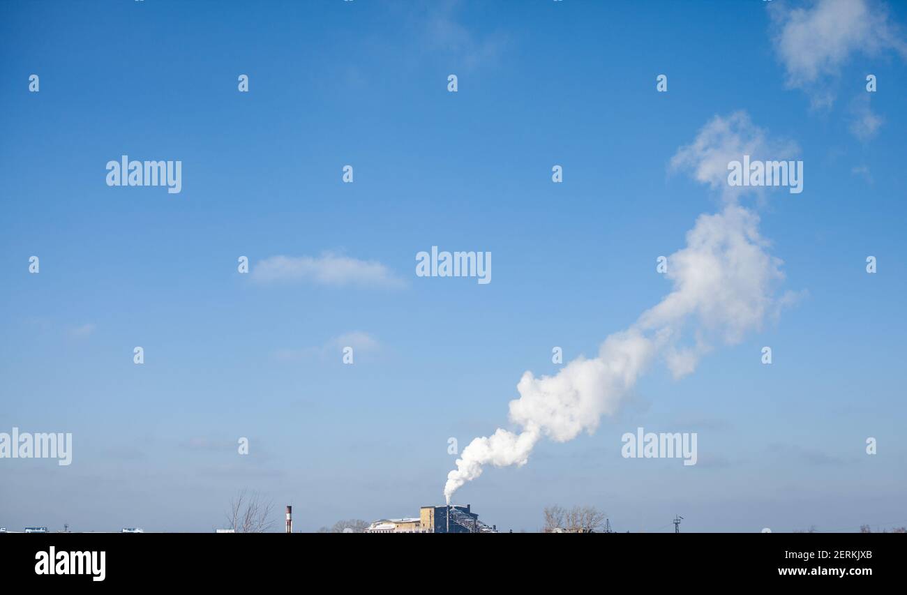 Fumo bianco spesso dal camino del locale caldaia. Fumo contro il cielo blu. Inquinamento atmosferico. Riscaldamento della città. Zona industriale. Foto Stock