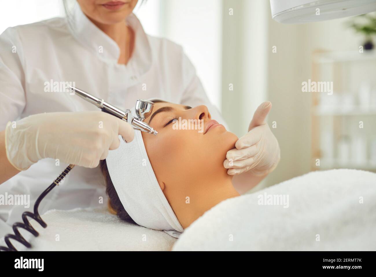 Mani di cosmetologa donna che fa la procedura dell'apparecchio di ossigeno facciale terapia per la giovane donna Foto Stock