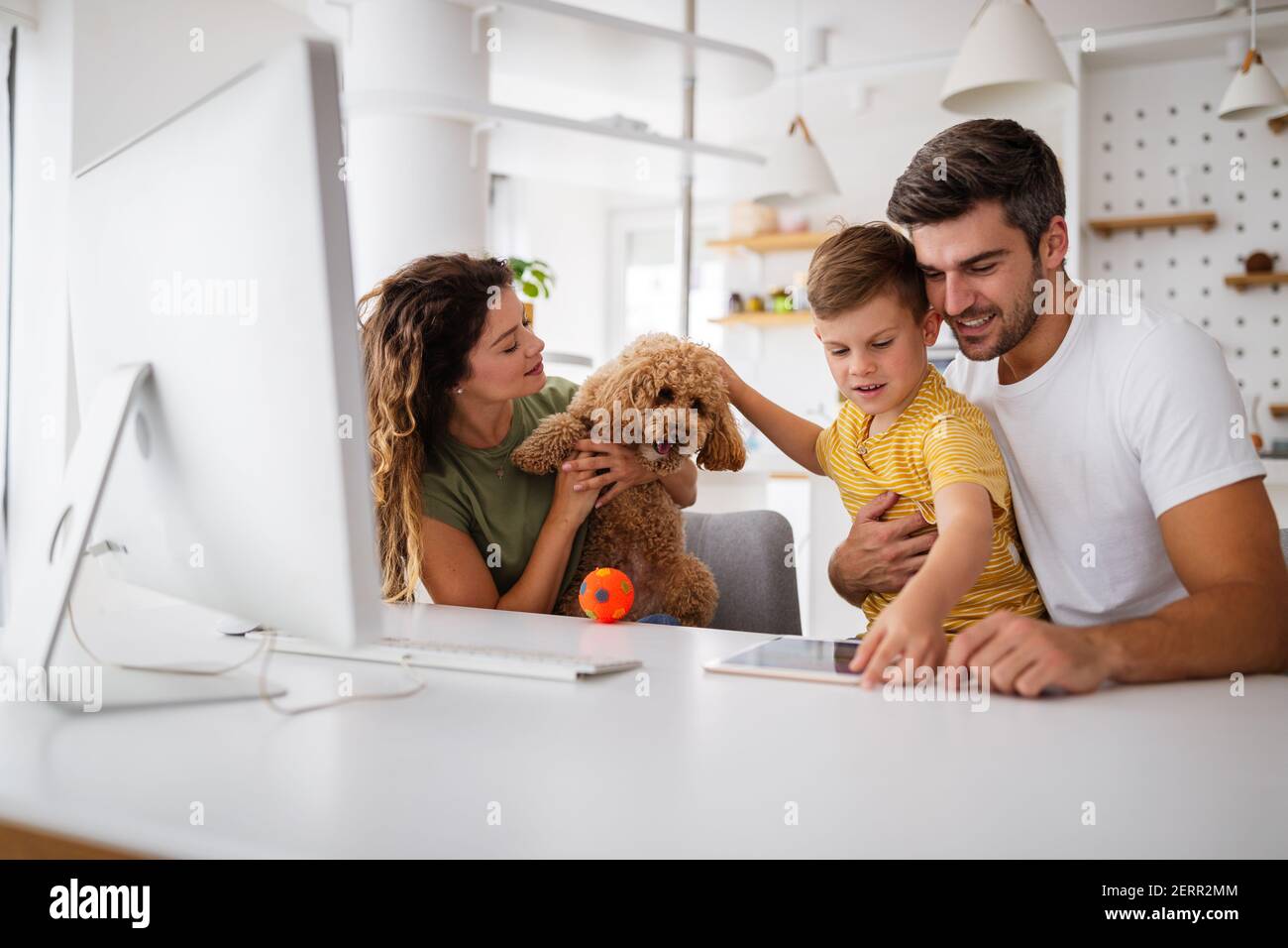 Felice famiglia con i dispositivi moderni e cane divertirsi, giocando a casa Foto Stock