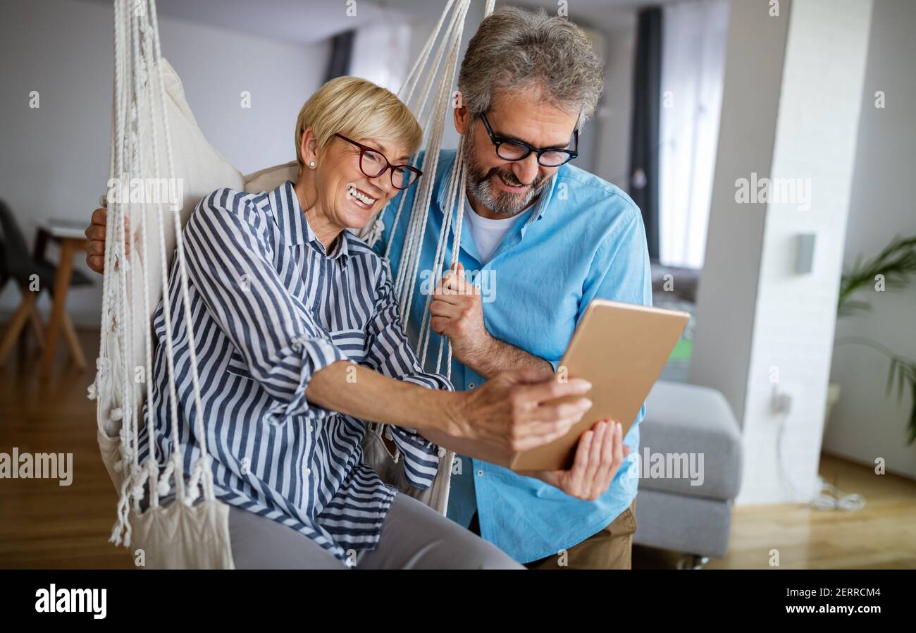 Felice coppia matura sorridente che usa il tablet digitale a casa Foto Stock