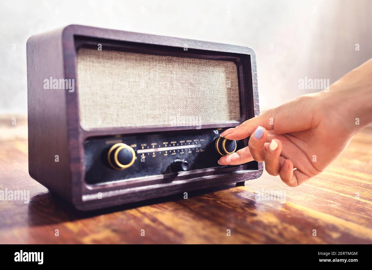 Sintonizzazione radio retrò. Donna che usa vecchie apparecchiature musicali vintage. Manopola di regolazione del volume o della frequenza. Attivazione o disattivazione del ricevitore o dell'altoparlante stereo. Foto Stock