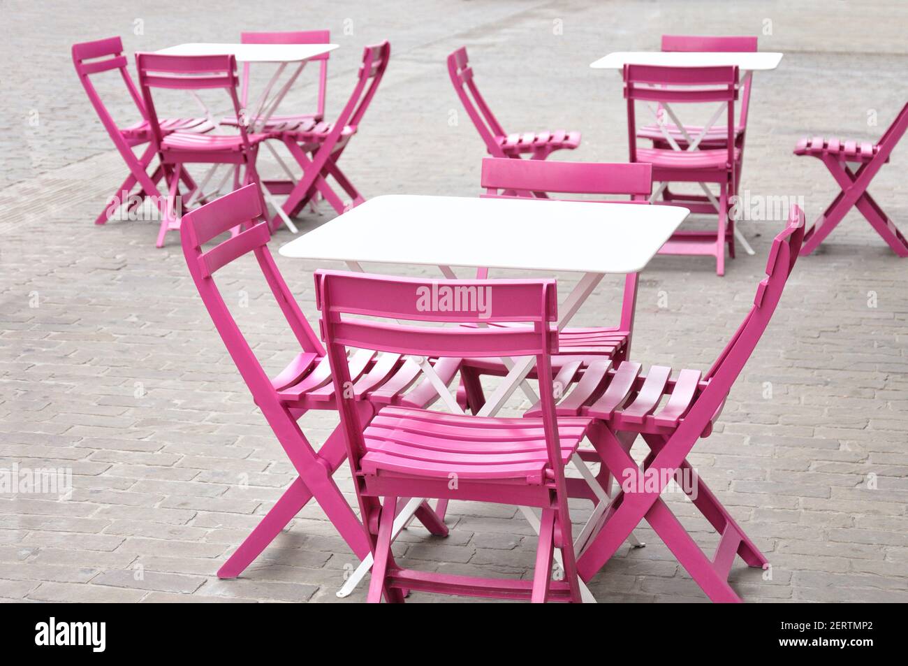 Graziosi tavoli bianchi e sedie rosa in un cafè su Una strada in una città in Europa Foto Stock