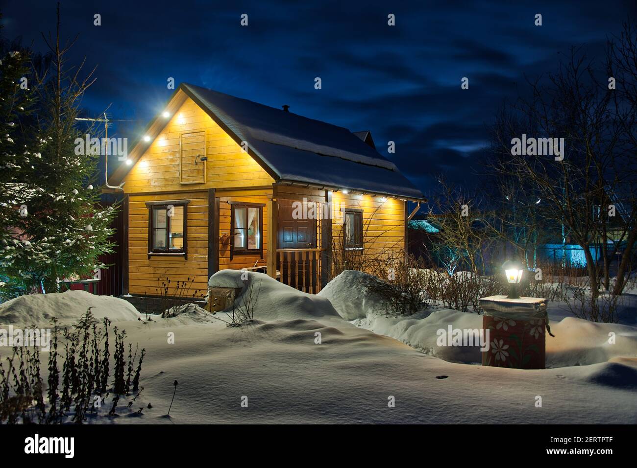 Casa di legno illuminata in un crepuscolo invernale Foto Stock