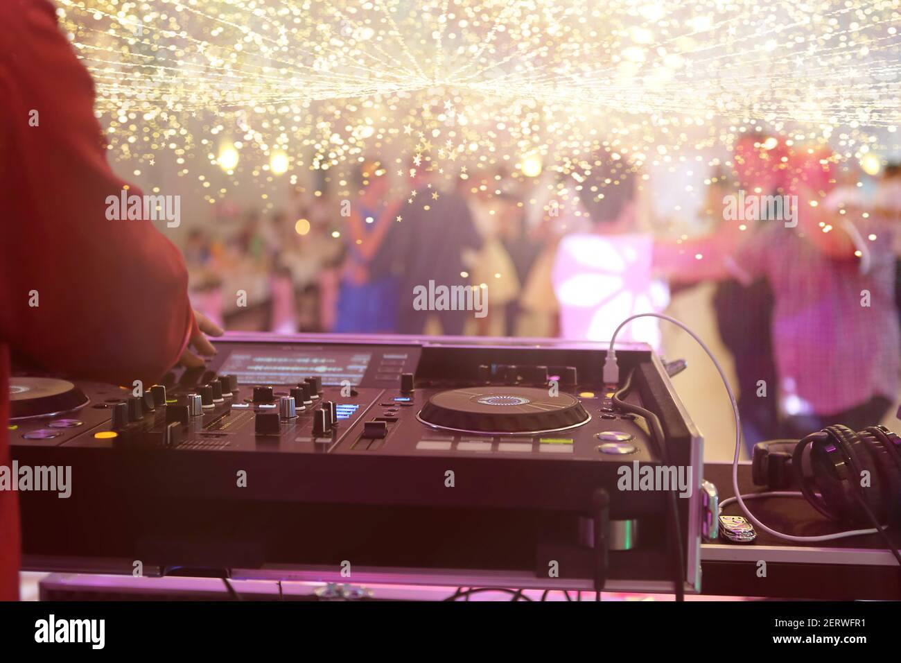 La console di mixaggio è suonata da DJ e coppie che ballano la pista da ballo sullo sfondo e spazio vuoto per testo Foto Stock