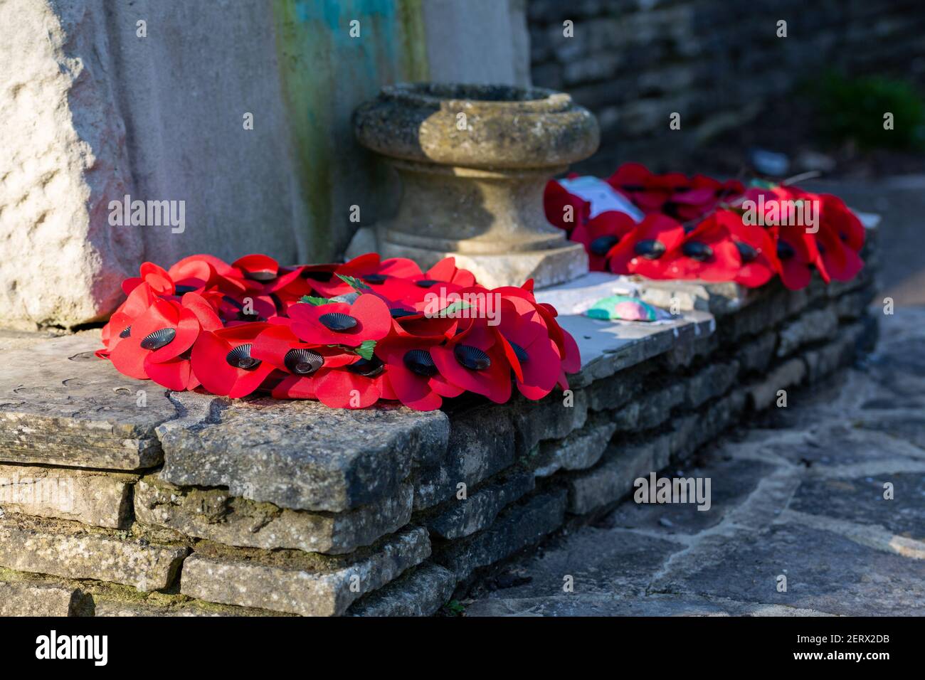 Corone di papavero poste ai piedi su un memoriale di guerra il giorno della memoria Foto Stock