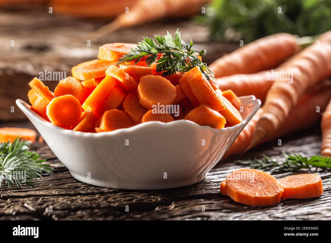 Affettato pezzi di carota in una ciotola e un fresco mazzo di carote sullo sfondo Foto Stock