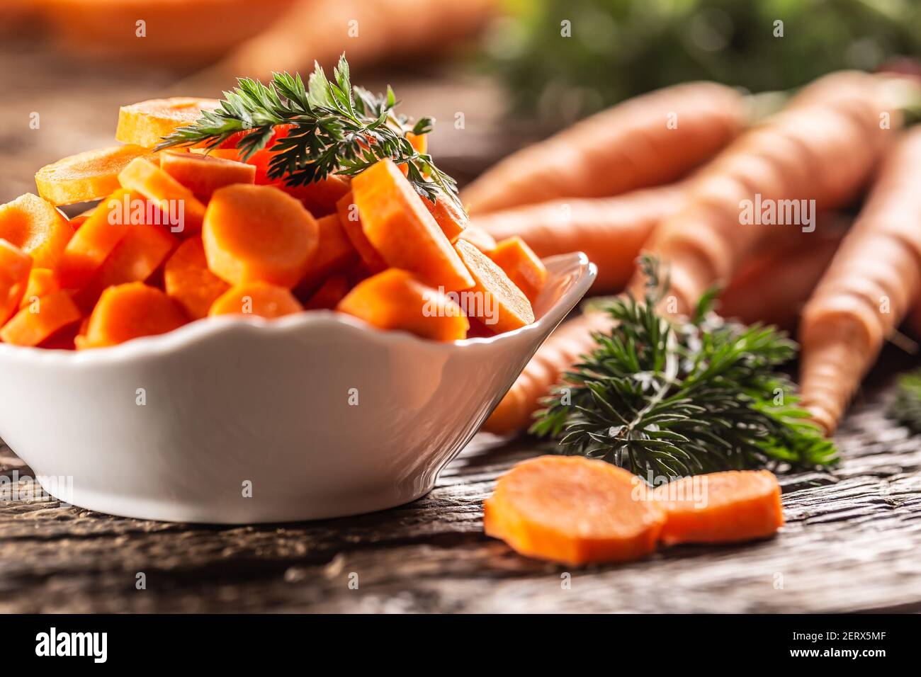 Affettato pezzi di carota in una ciotola e un fresco mazzo di carote sullo sfondo Foto Stock