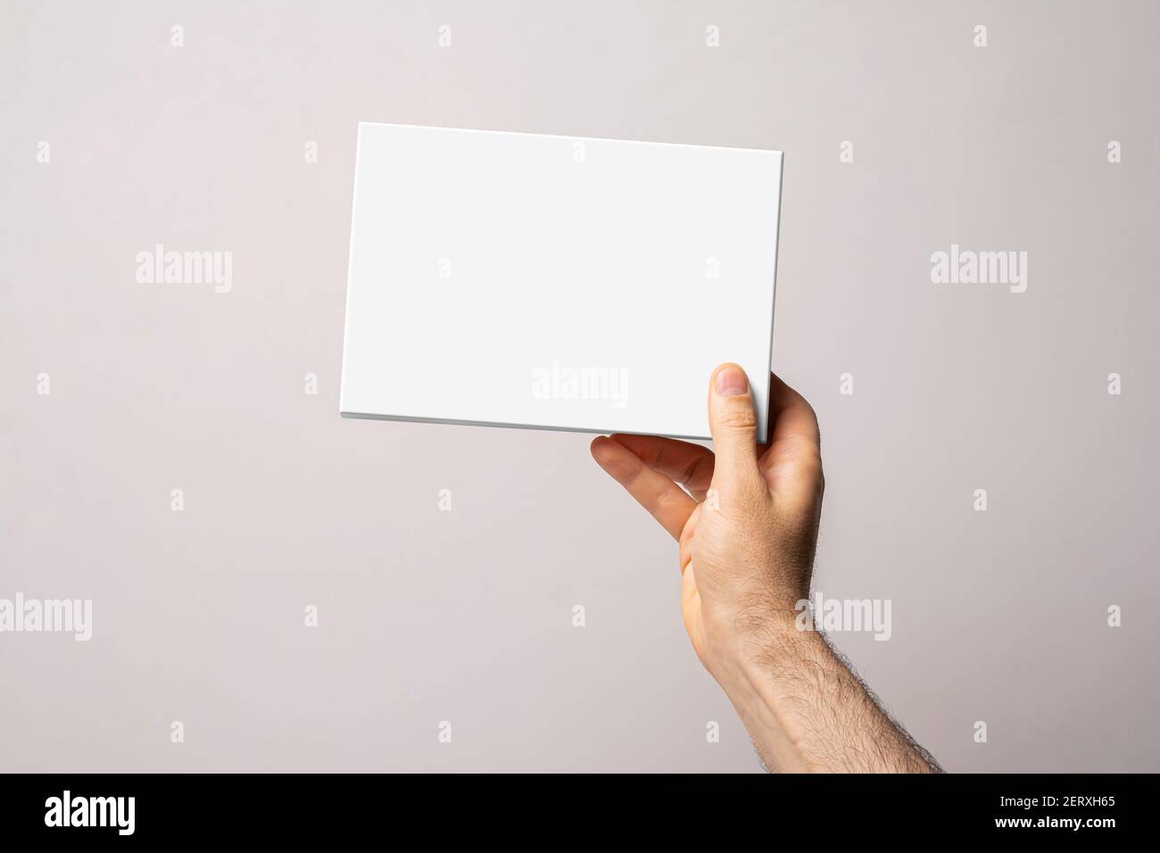 Una mano maschio che tiene un modello di serie mock-up modificabile in scatola rigida pronto per il progetto, incluso il percorso di selezione delle facce. Foto Stock