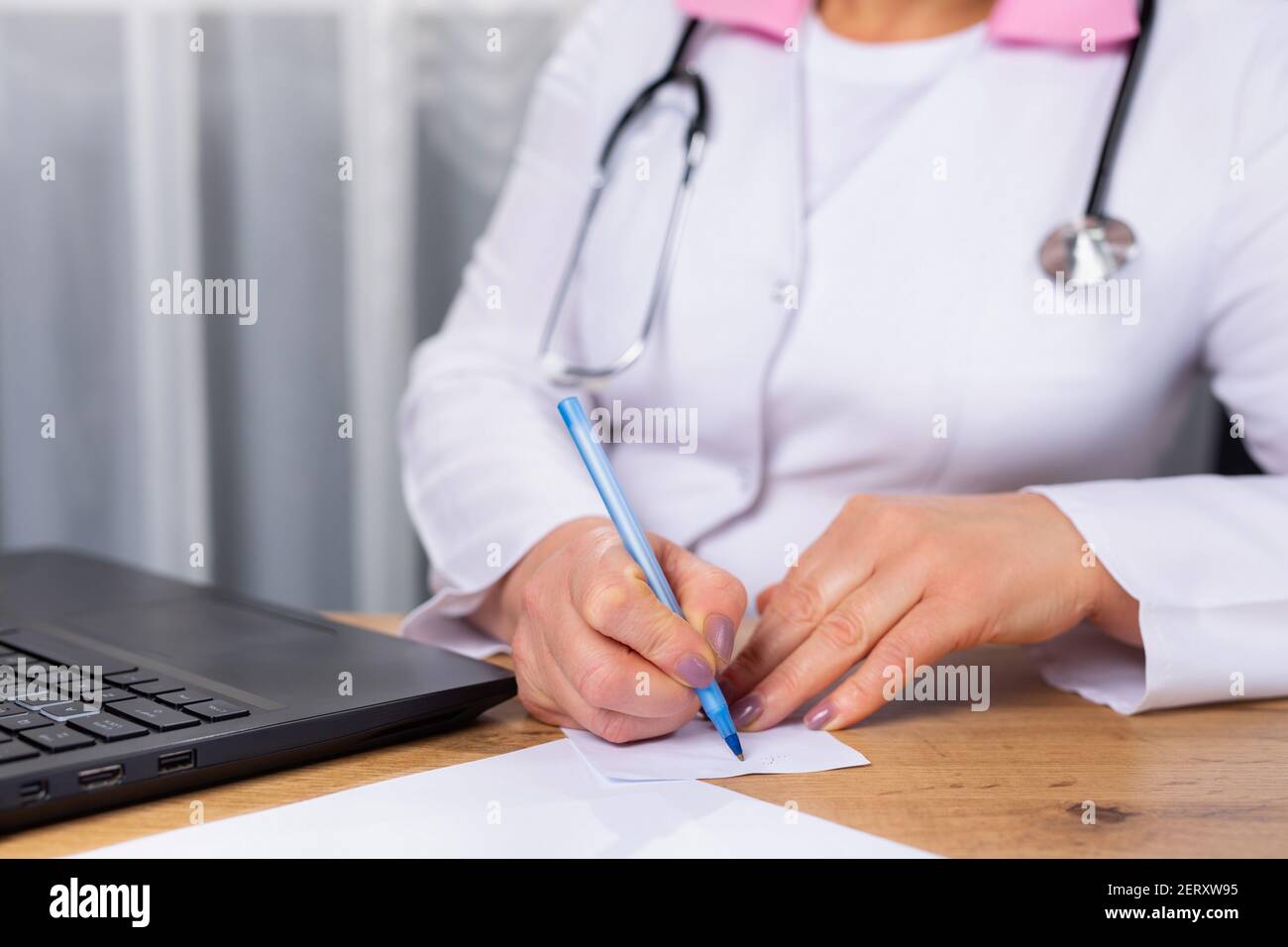 Foto ritagliata di un medico terapeuta seduto ad un tavolo di fronte ad un computer. Registrazione della corretta leccatura. Preparazione. Ricetta. Foto Stock