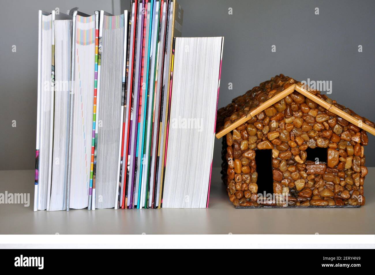 Libri, pila di nuovi libri su tavola di legno con casa di pietra come supporto, Brasile, Sud America Foto Stock