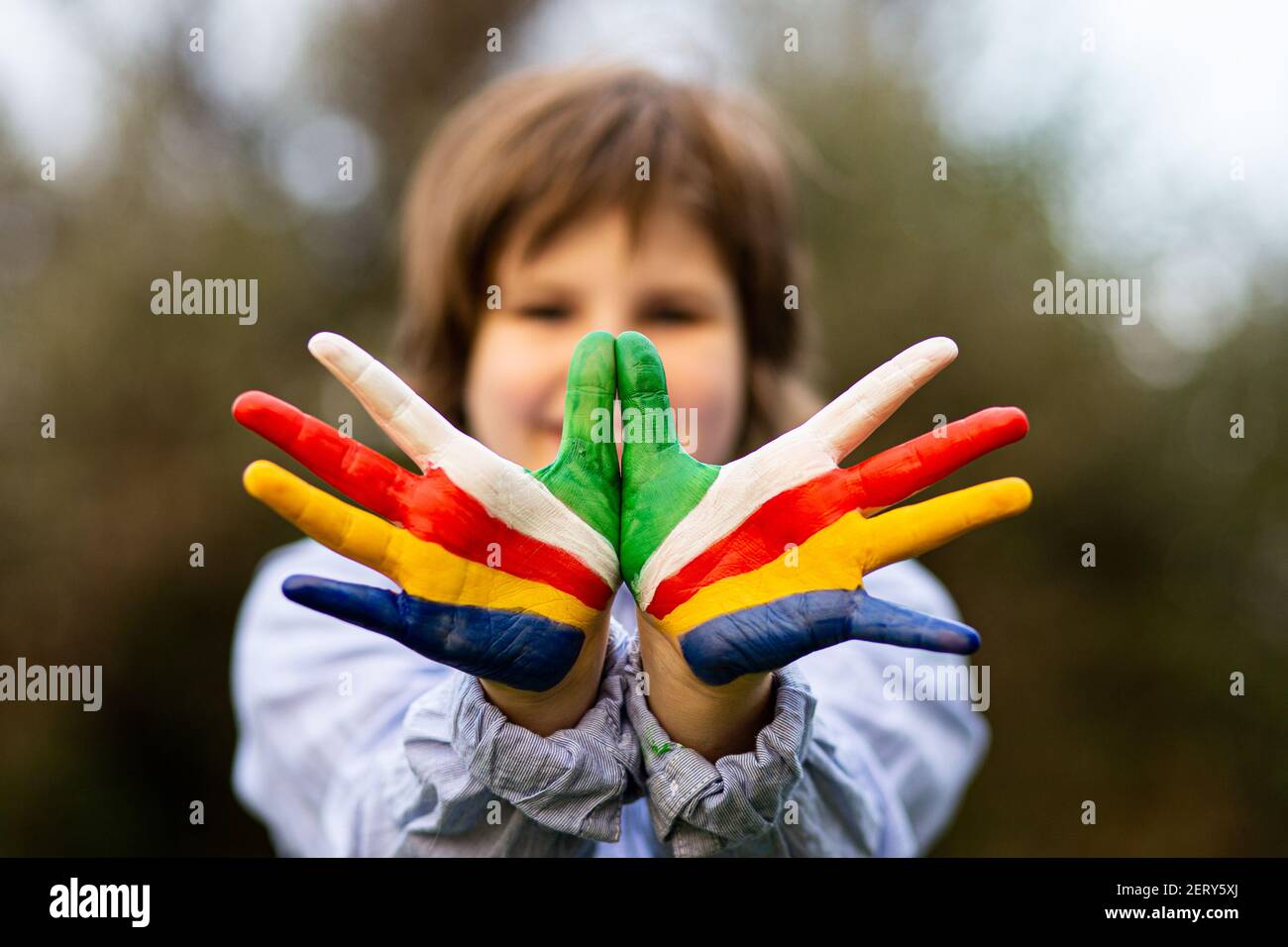 Concetto Freedom Seychelles. Carino bambino che forma il gesto dell'uccello di volo con le mani dipinte nei colori della bandiera delle Seychelles. Concentrarsi sulle mani Foto Stock