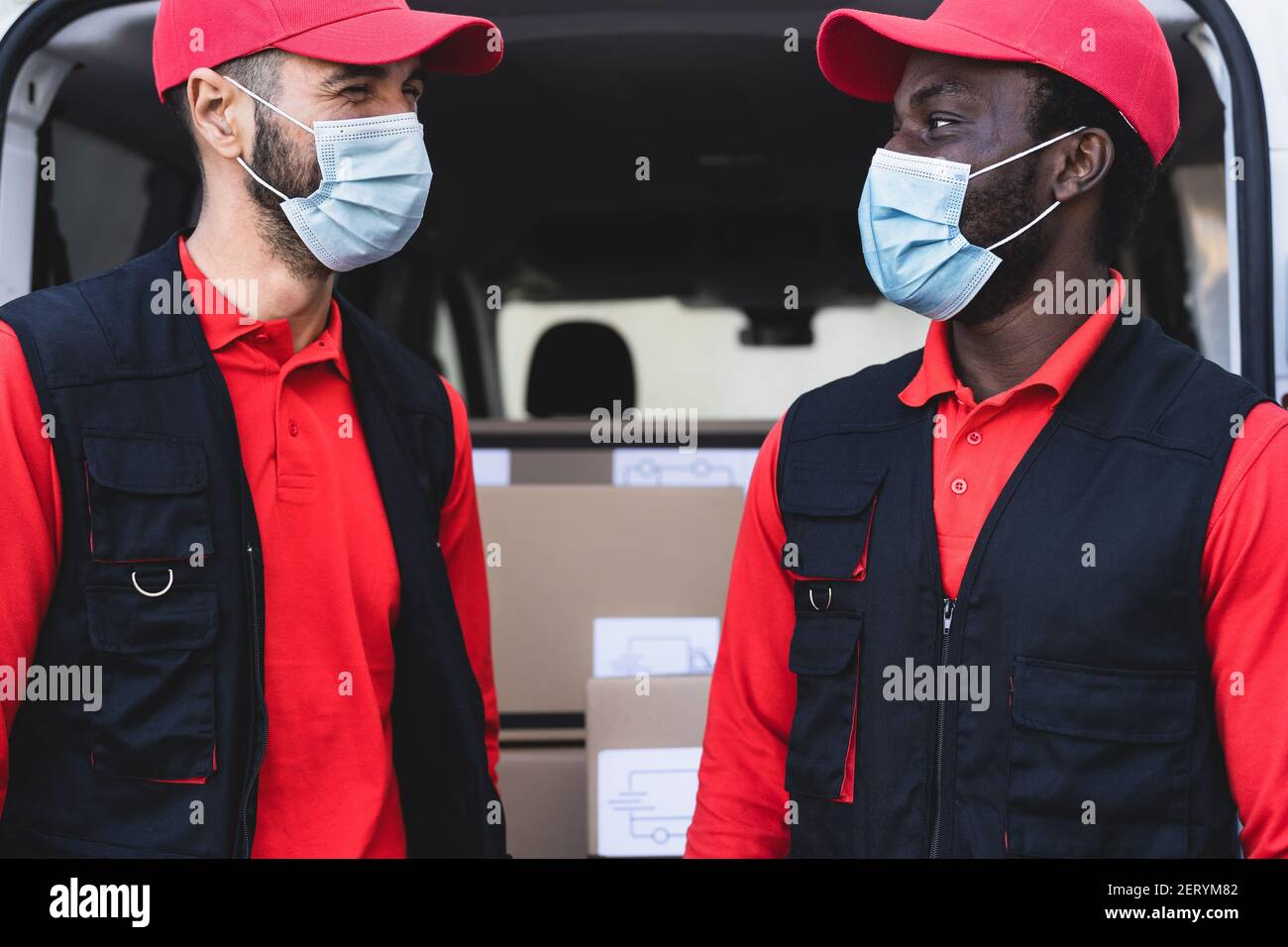 Giovani uomini di consegna che lavorano mentre indossano la maschera per evitare diffusione del virus corona - persone che lavorano con consegna rapida durante focolaio del virus corona Foto Stock
