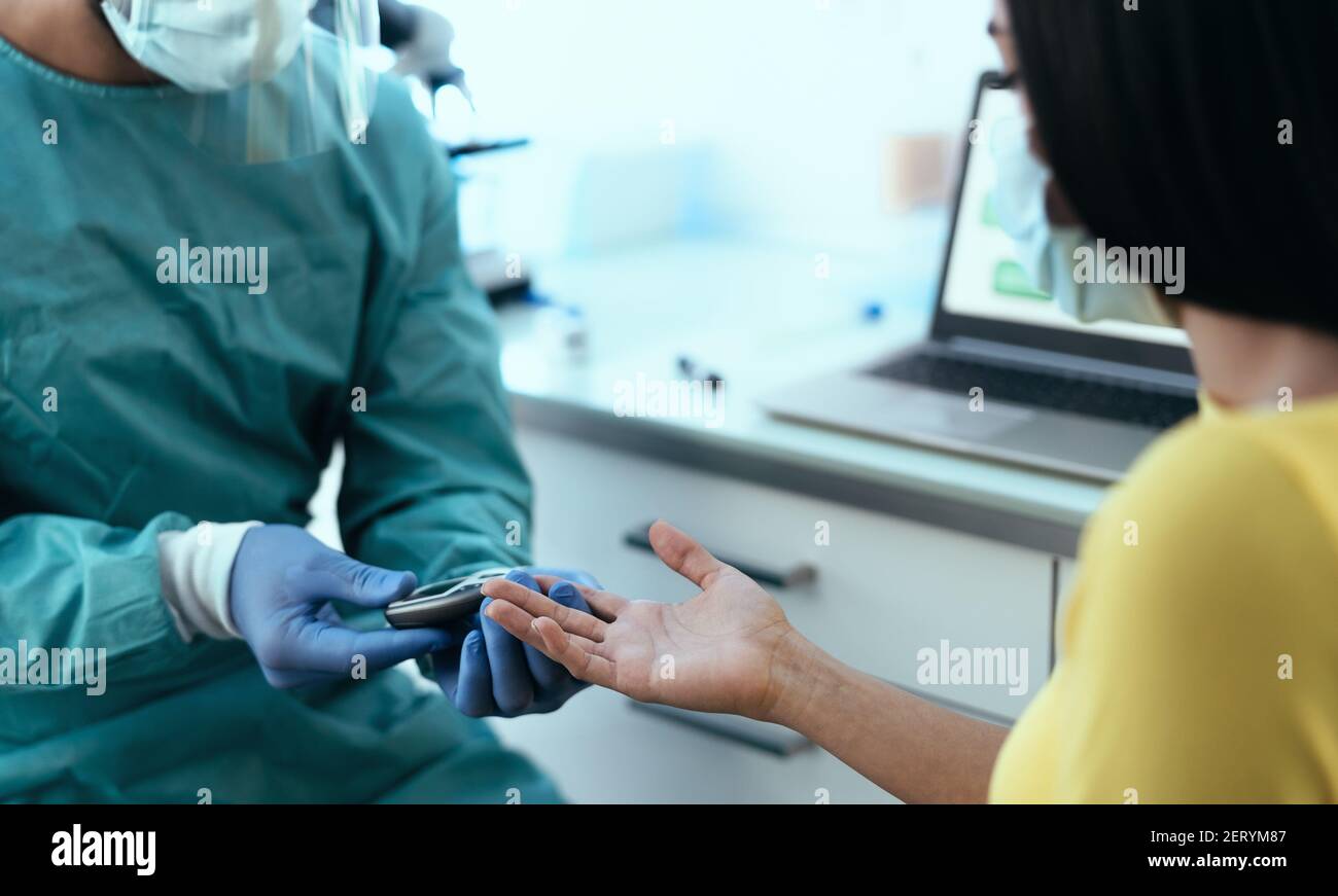 Lavoratore medico controllo glicemia test per il diabete a paziente femminile Durante l'epidemia di virus corona - concetto sanitario Foto Stock