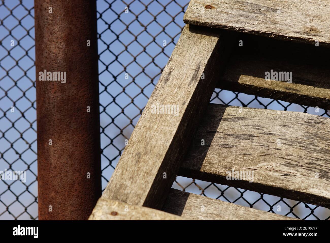 Closeup vecchio pallet di legno vicino ad una recinzione di rete arrugginita Foto Stock