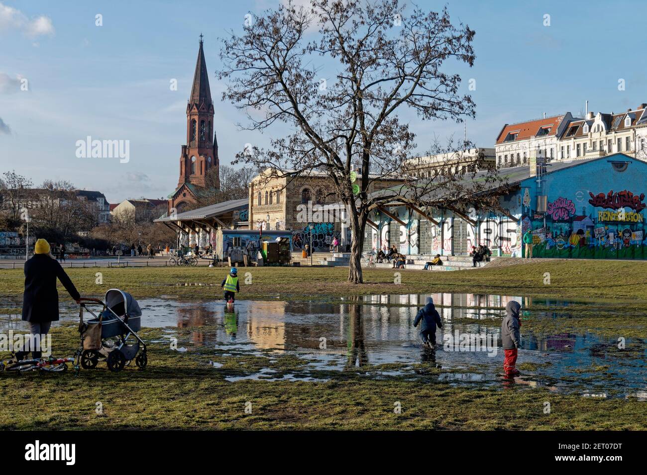 Kinder spielen in kleiner See aus geschmolzenen EIS im Goerlitzer Park, Tauwetter, Berlino, Foto Stock