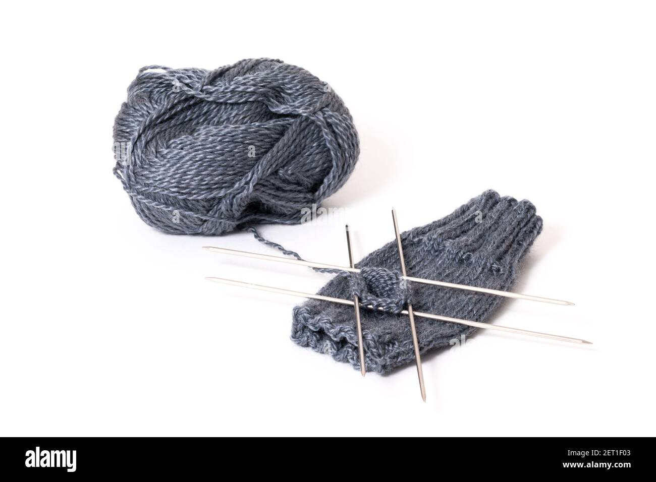 Iniziare a lavorare a maglia su quattro aghi da maglieria. Aghi per maglieria e lana isolati su sfondo bianco Foto Stock