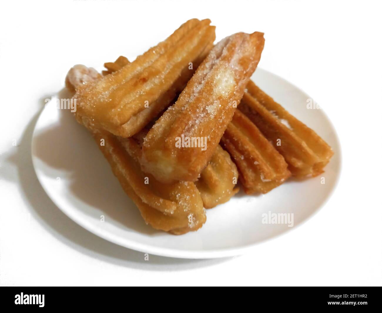Churros dolci zuccherati, pasta fritta argentina tradizionale di origine spagnola, su piastra isolata su fondo bianco. Angolo alto. Messa a fuoco selettiva Foto Stock
