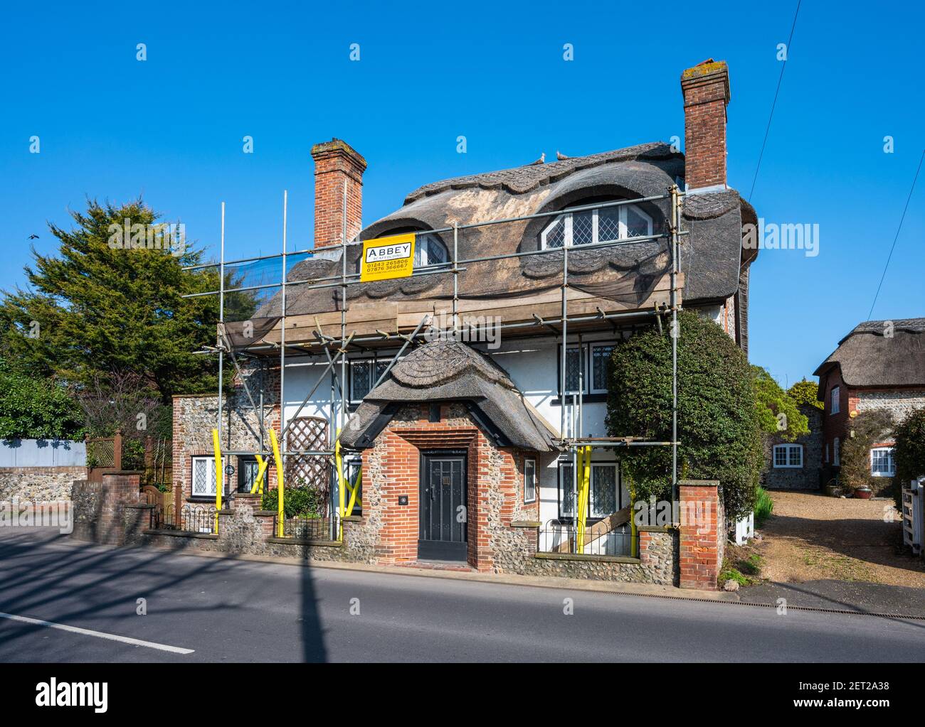 Cottage con tetto in paglia in fase di manutenzione con ponteggi eretti intorno all'esterno del cottage. Situato a Rustington, West Sussex, Inghilterra, Regno Unito. Foto Stock