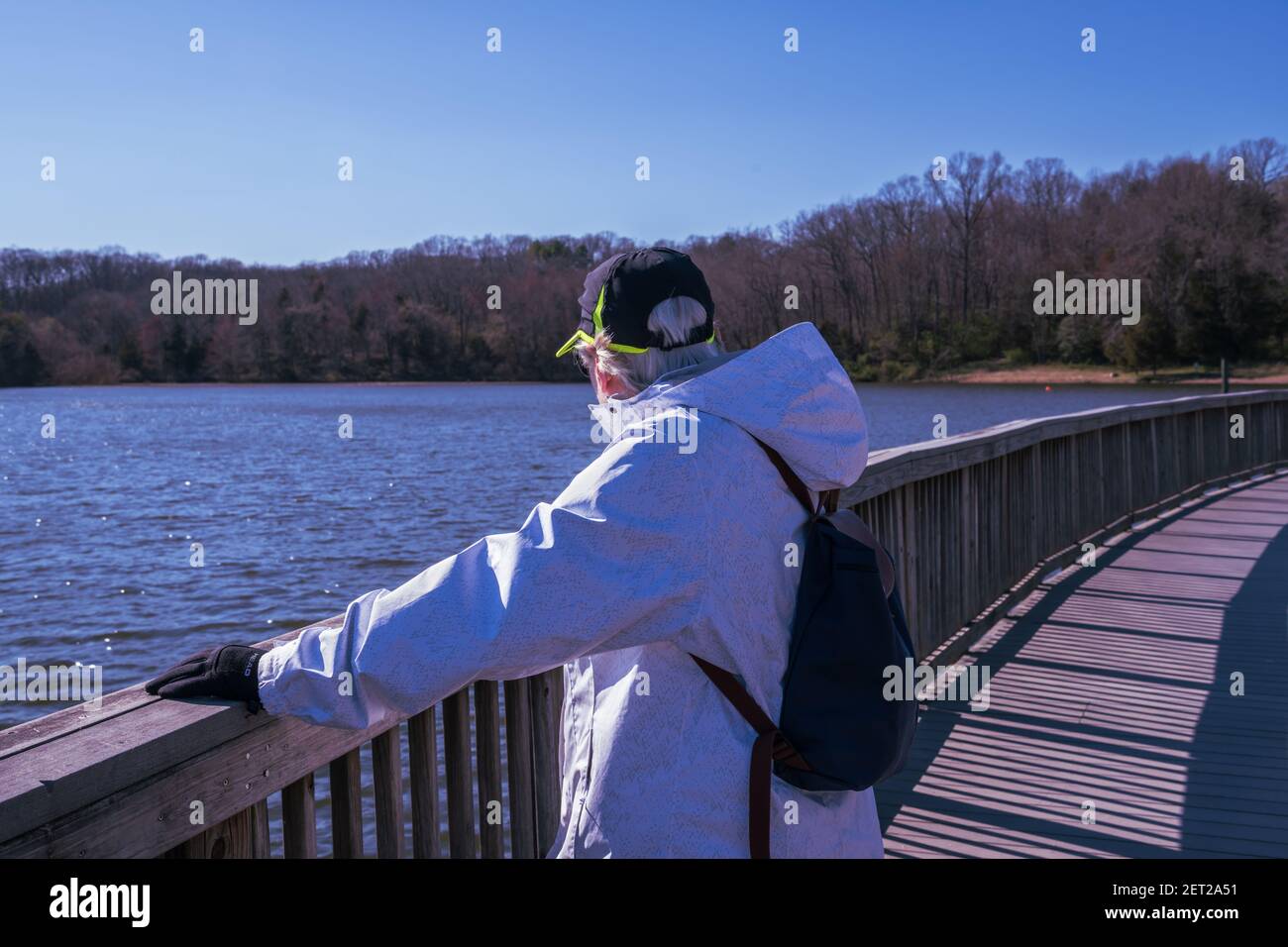 Foto di una donna che guarda con attenzione verso la lontana riva sul lago Fairfax in una giornata fredda in primavera nella Virginia del Nord. Foto Stock