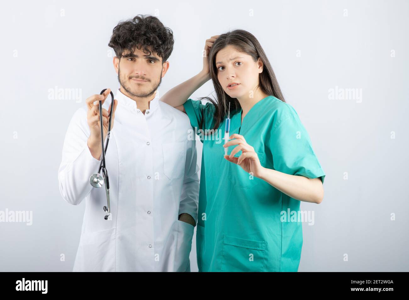 Medico di sesso maschile che tiene lo stetoscopio vicino a un'infermiera di sesso femminile che contiene la siringa Foto Stock