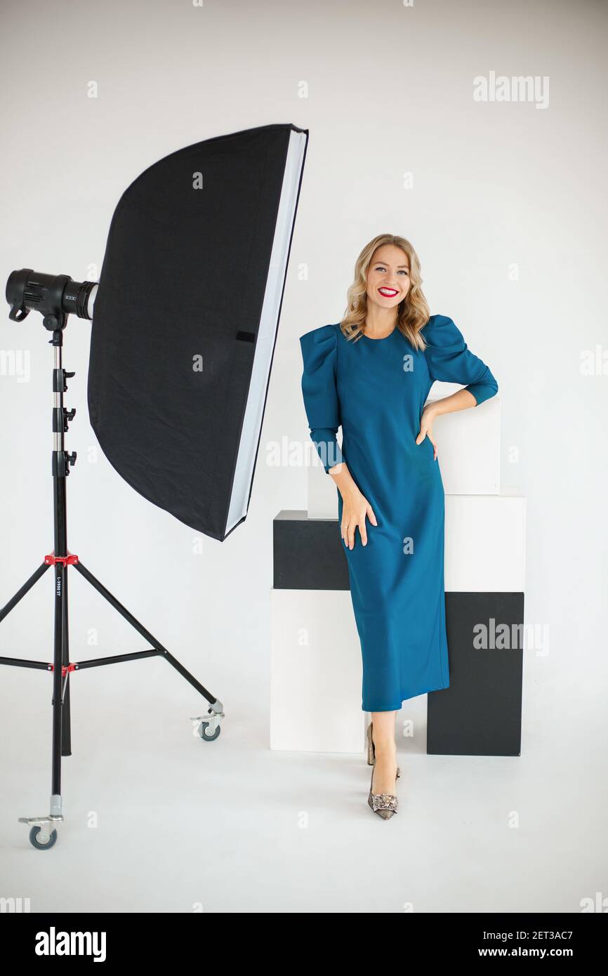 Sorridente fiducioso giovane bella donna d'affari in abito blu posa con attrezzatura fotografica Foto Stock