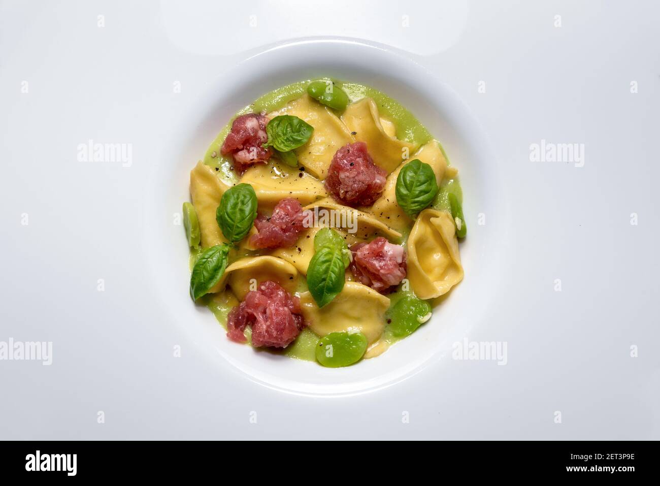 Ravioli del plin con salsa ai fave, salsiccia di Bra e foglie di basilico, tipica pasta ripiena delle Langhe, Italia. Vista dall'alto Foto Stock