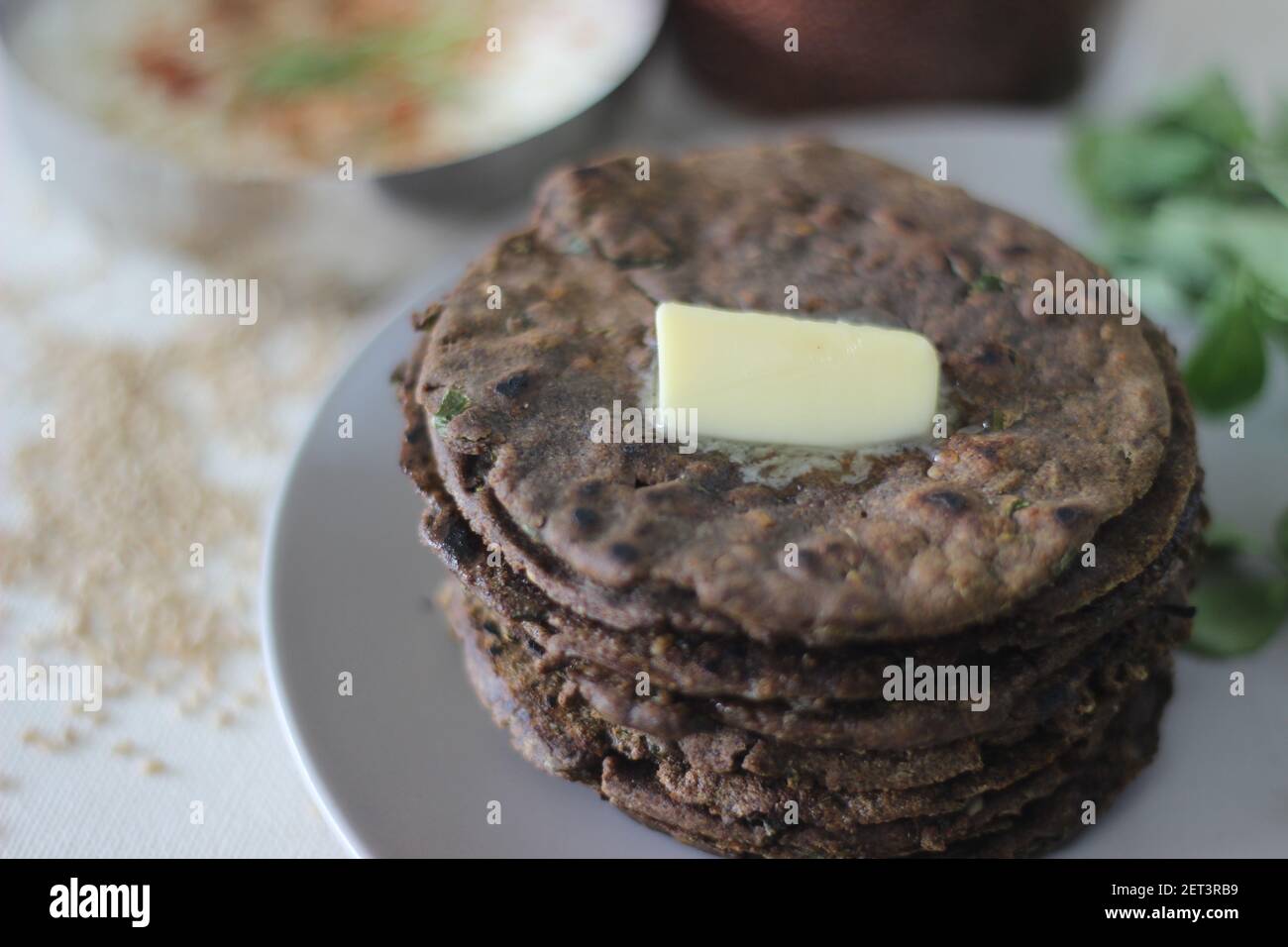 Pane piatto con finger millet e foglie di fenugreek servito con cagliata di masala. Si chiama anche Nachni methi thepla, un pane piatto sano e gustoso da Foto Stock