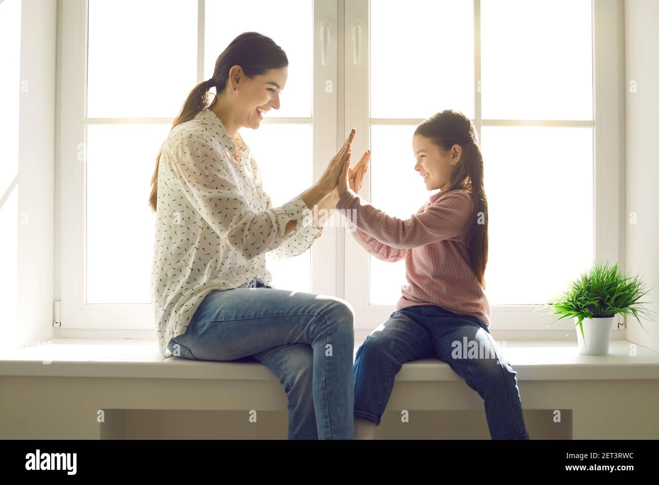 Mamma e figlia allegre che giocano giochi divertenti con la figlia piccola che si aggrappano le mani. Foto Stock