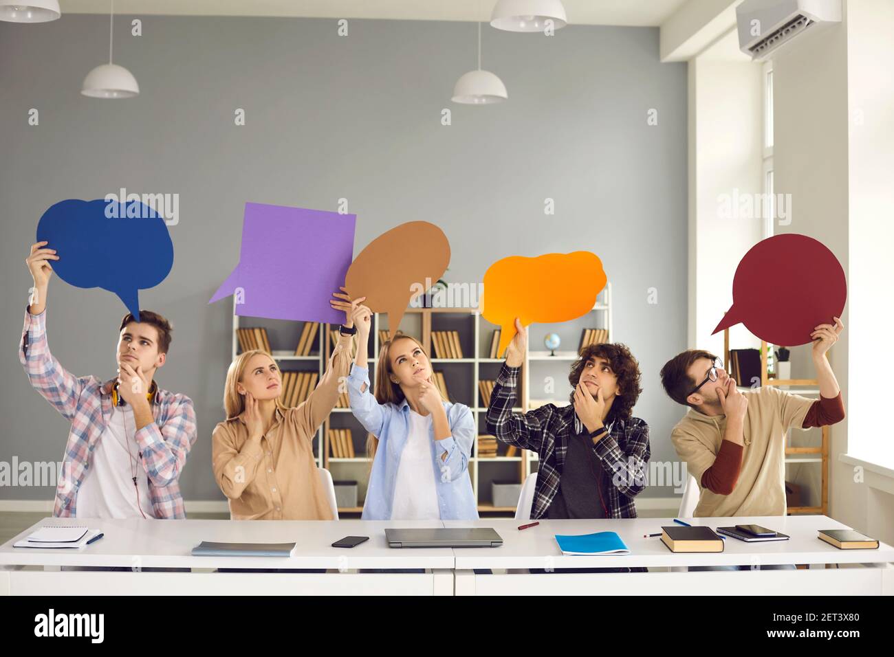 Gli studenti universitari perplessi che tengono bolle di pensiero e pensano alla risposta per provare la carta Foto Stock