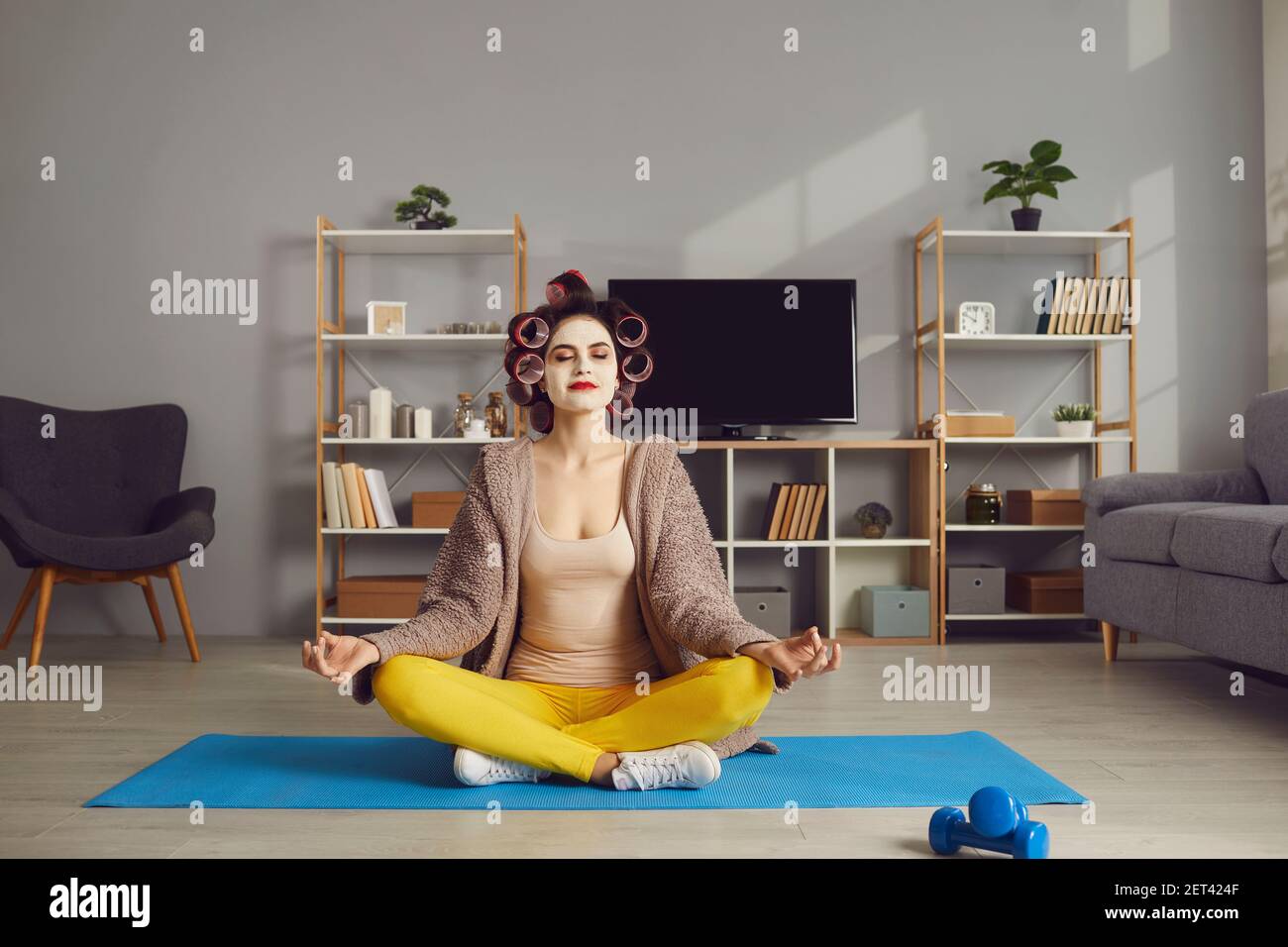 Donna felice seduta sul tappeto yoga, rilassante, godendo di meditazione e tempo di cura di sé Foto Stock