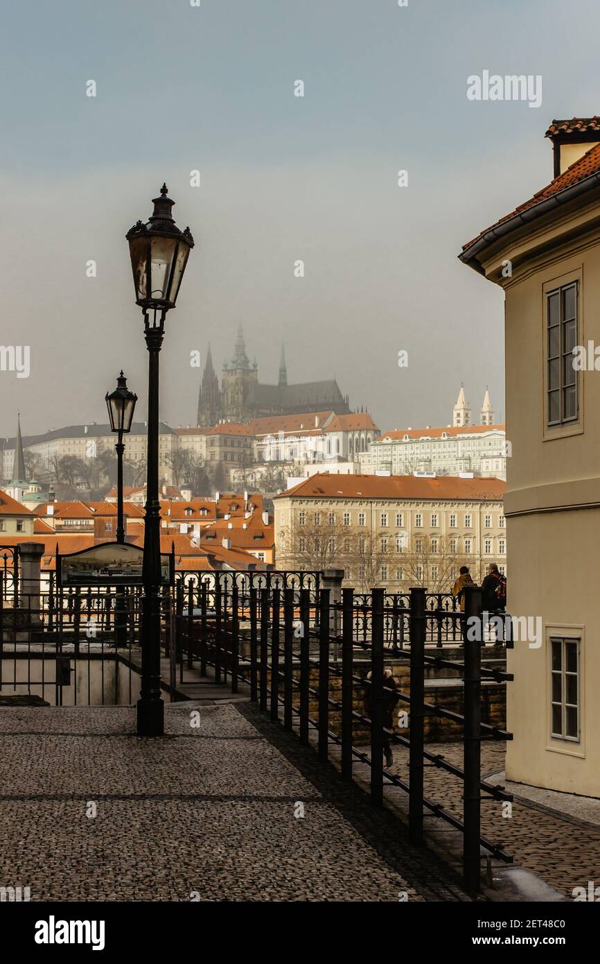 Splendida vista sulla strada pedonale di ciottoli e sul Castello di Praga nella nebbia mattutina. Tranquilla scena cittadina. Camminando attraverso la capitale vuota della Czechia Foto Stock