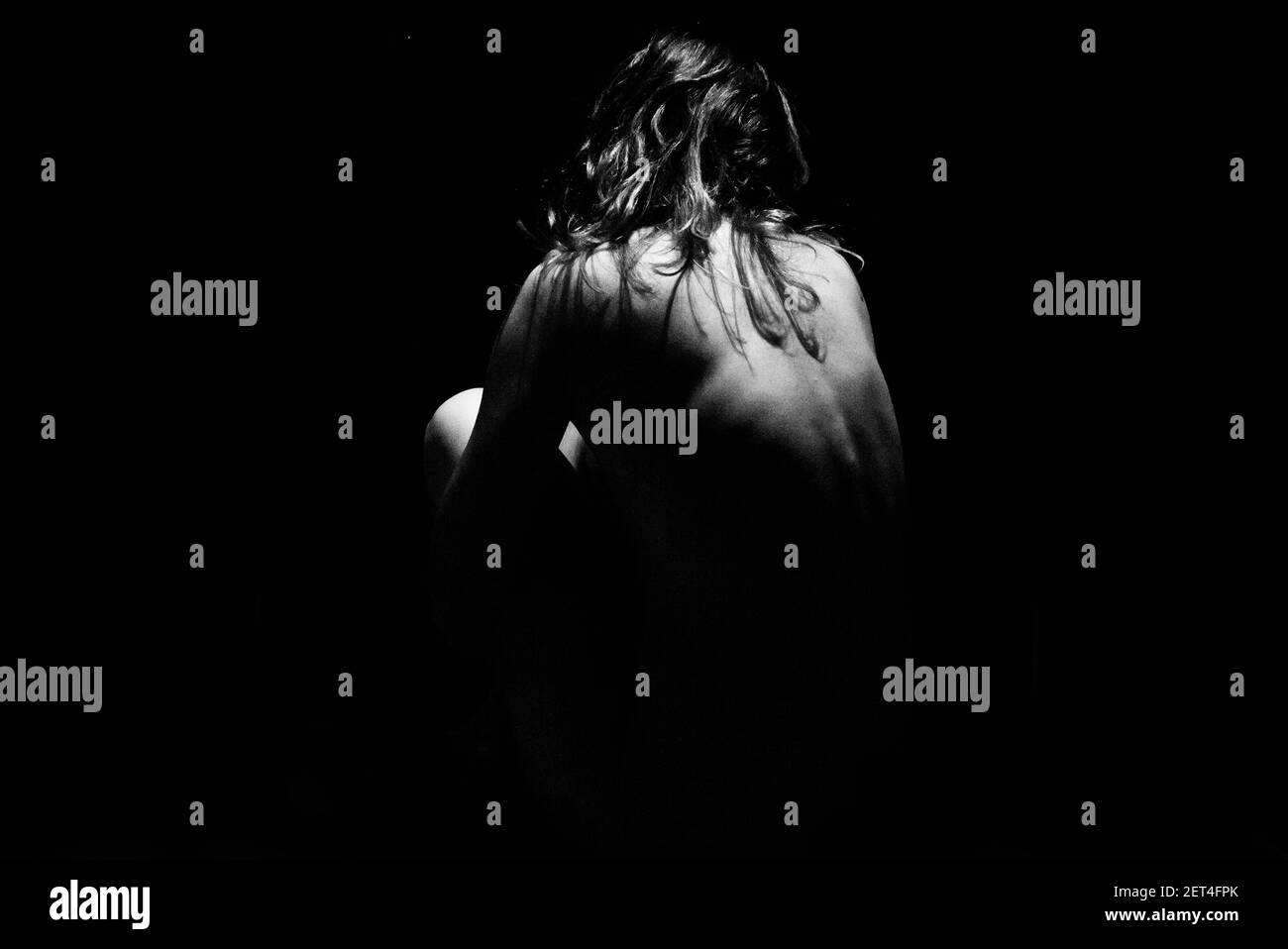 Vista posteriore di una donna nuda seduta all'ombra Foto Stock