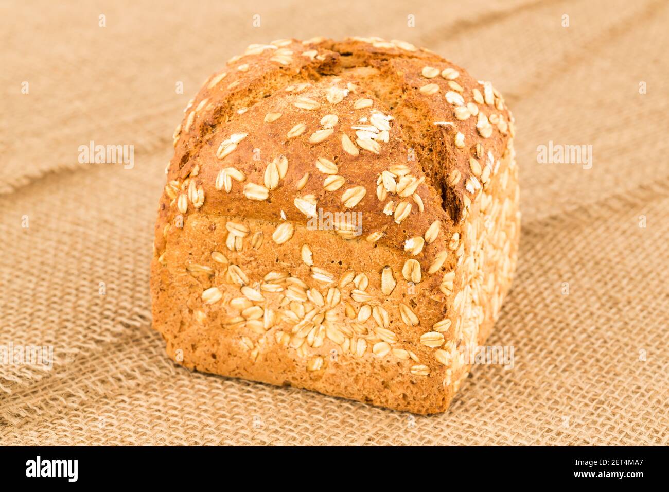 Pane integrale con avena sullo sfondo del burlap. Foto Stock