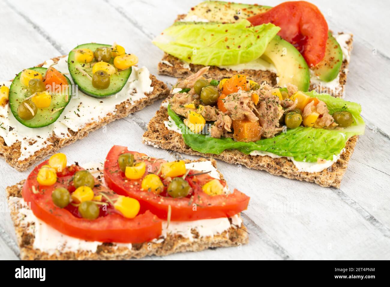 Panini con cracker, formaggio, tonno e verdure su sfondo grigio di legno. Foto Stock