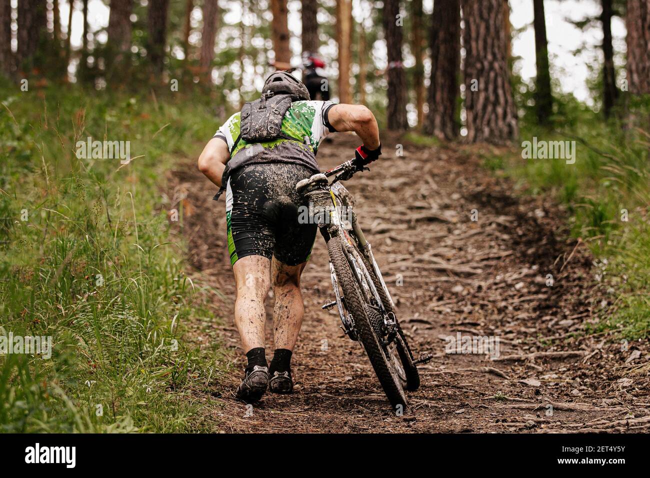 ciclista sporca con mountain bike salita su sentiero forestale Foto Stock