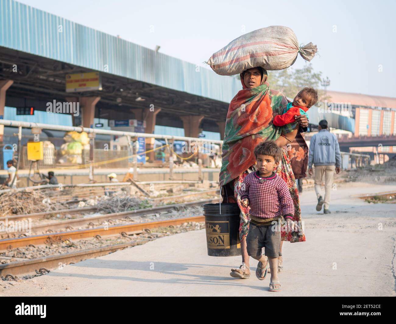 Jaipur, India. 09-05-2018. Madre che porta il suo bambino e nelle sue braccia così come alcuni effetti sulla sua testa sta camminando con il suo figlio al treno principale Foto Stock