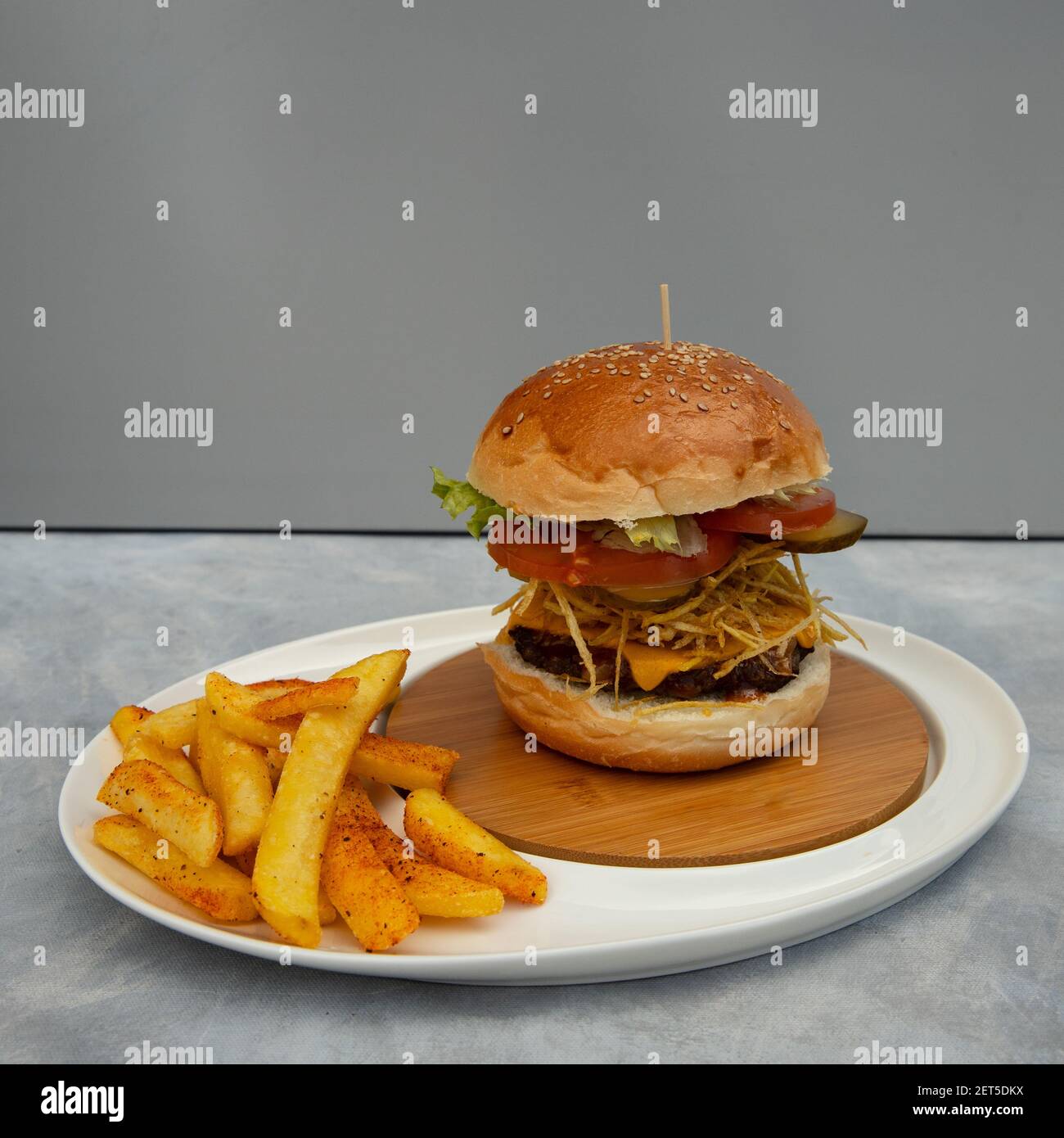 Hamburger e patatine fritte pronti su sfondo grigio e. sottopiano blu Foto Stock
