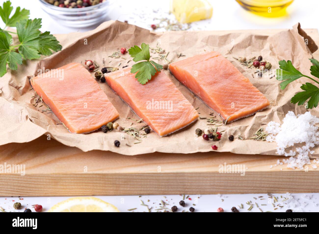 Tre filetti di salmone fresco crudo con spezie ed erbe sul tagliere. Foto Stock