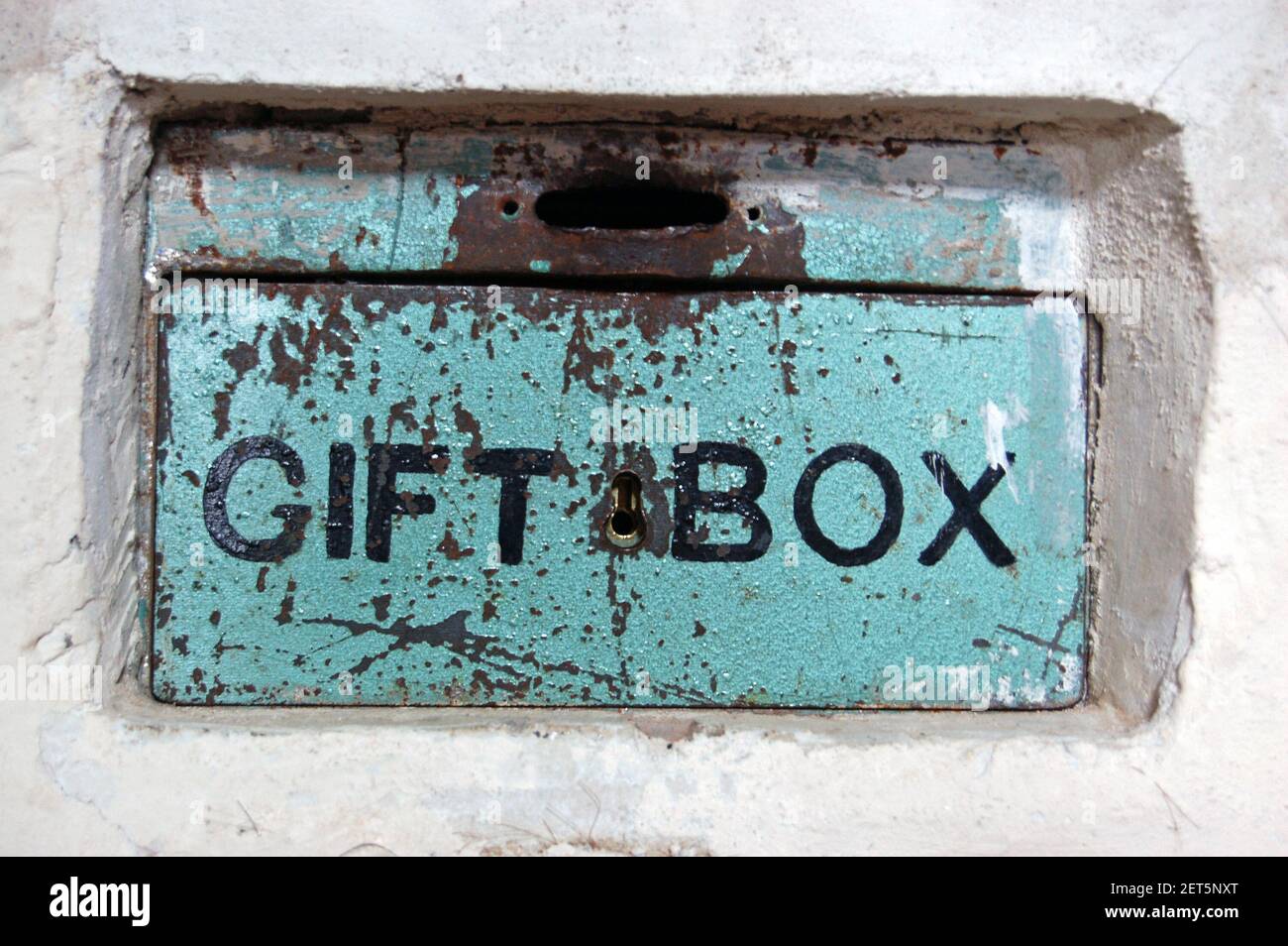 Una scatola di beneficenza cementata in un muro di pietra per raccogliere le monete donate. Foto Stock