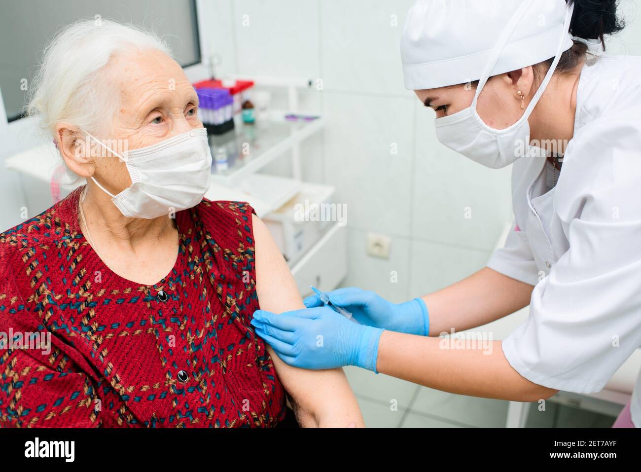 il medico o l'infermiere inietta un farmaco o un vaccino nella spalla di una donna anziana. Foto Stock