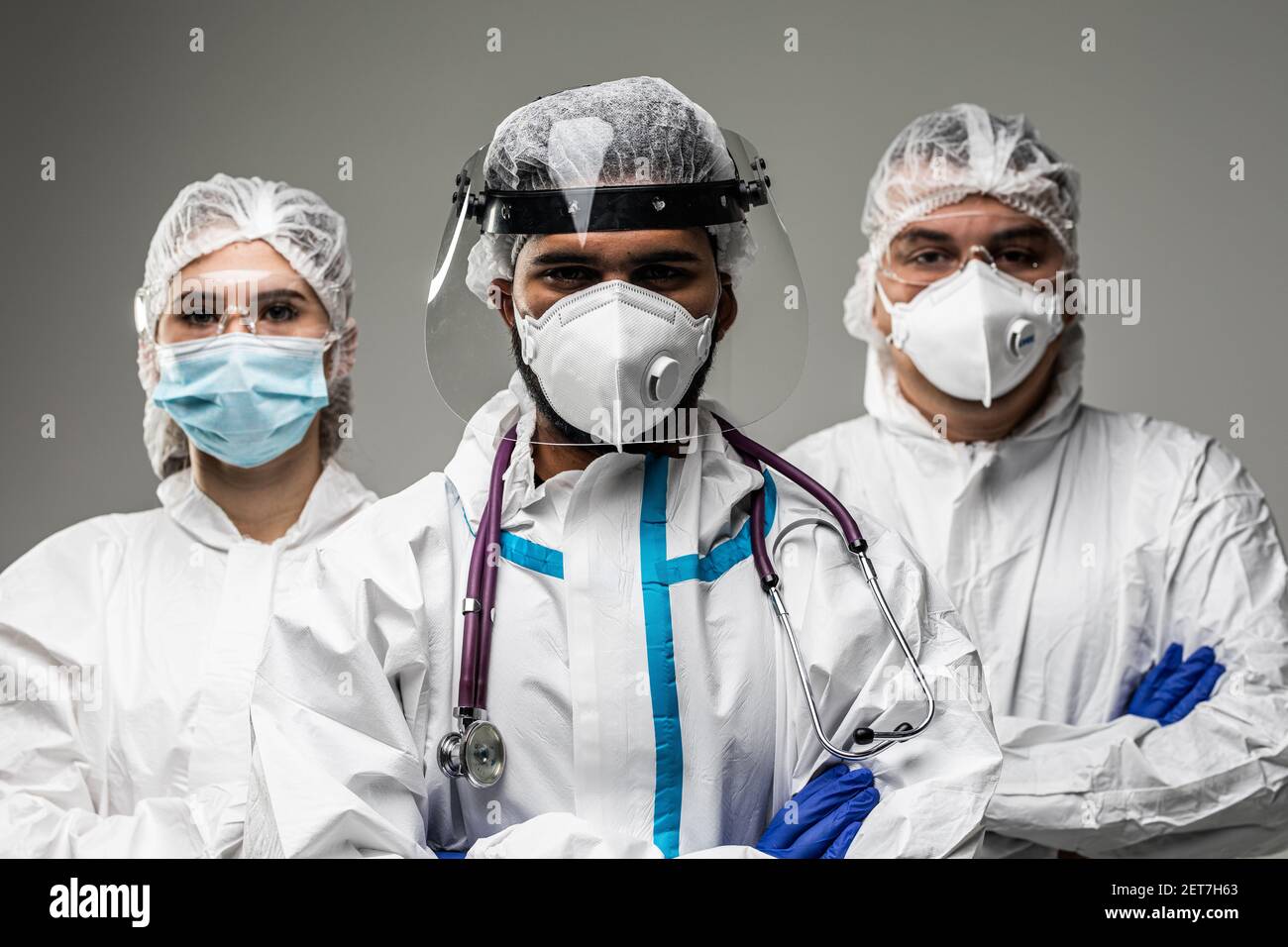 Tre operatori medici in strumenti di protezione contro i rischi biologici isolati su sfondo grigio. Pronto a combattere con covid19. Foto Stock