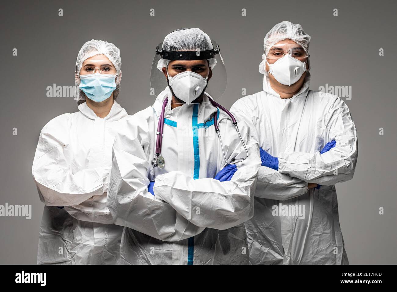 Tre operatori medici in strumenti di protezione contro i rischi biologici isolati su sfondo grigio. Pronto a combattere con covid19. Foto Stock