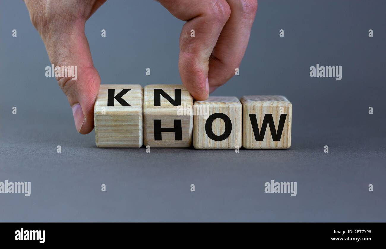 Conoscere il simbolo. L'uomo d'affari gira i cubi e cambia la parola 'come' a 'sapere'. Splendido sfondo grigio. Spazio di copia. Business e know how concetto. Foto Stock