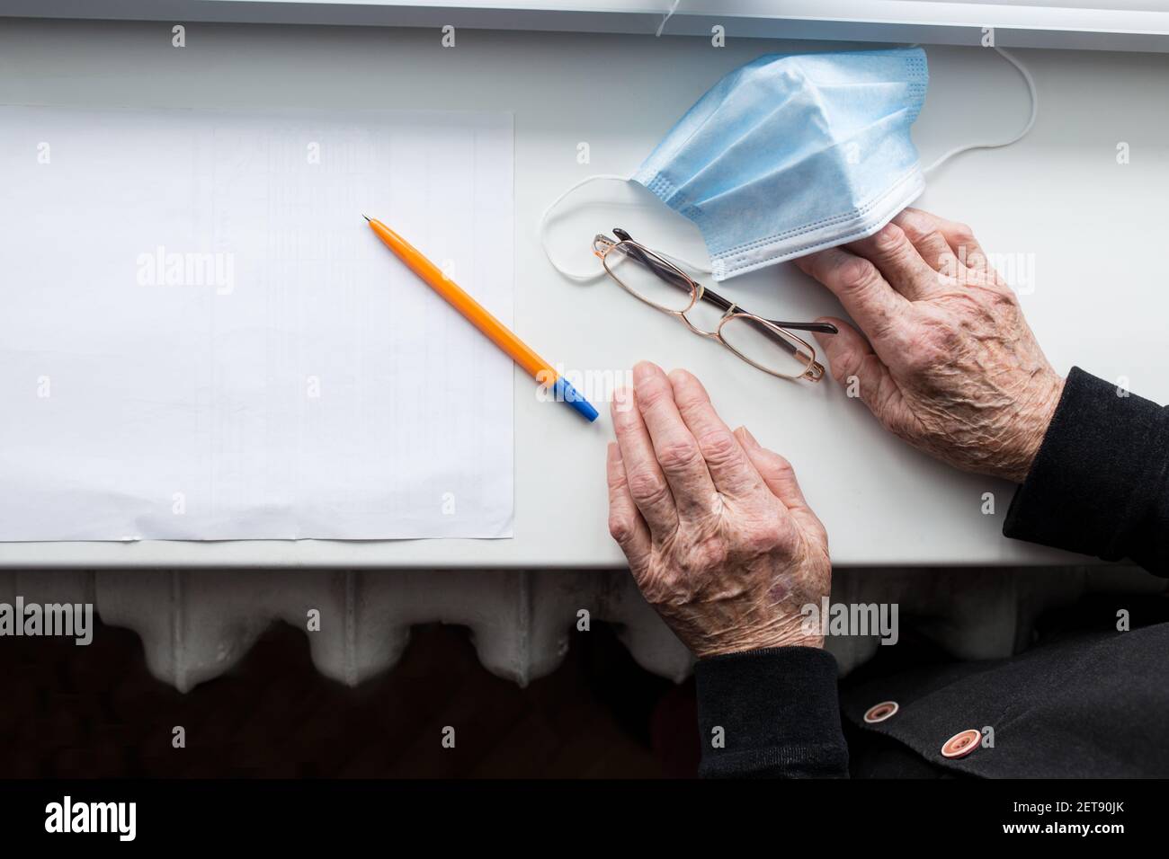 Lista di controllo per auto-isolamento e mani di vecchio umano vicino a. finestra Foto Stock