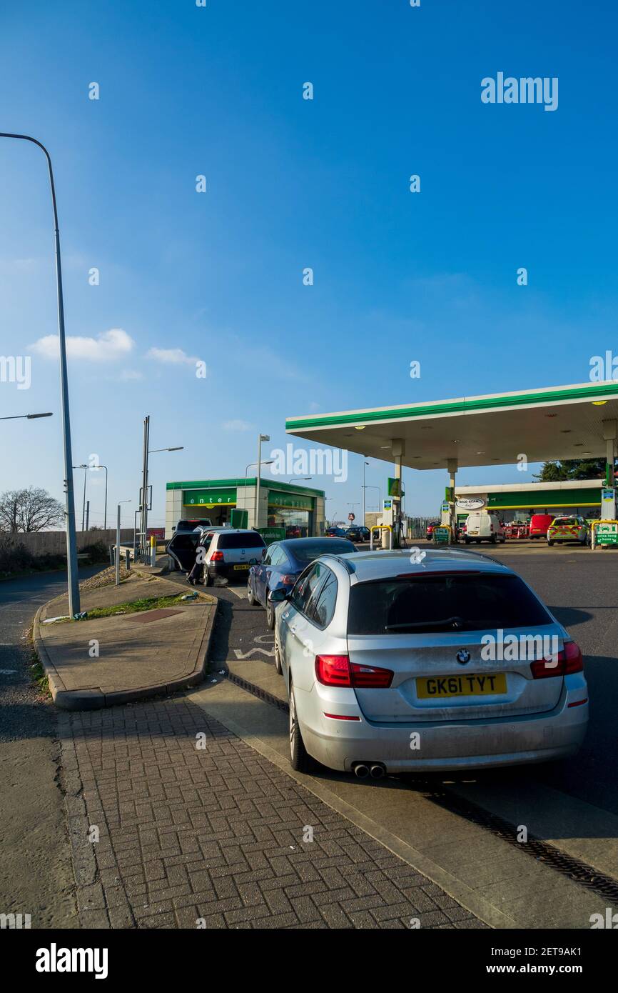 Una coda di auto presso il lavaggio automatico di auto su un piazzale di rifornimento BP in un pomeriggio soleggiato di domenica. Foto Stock